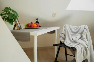 a white table with a bowl of fruit and a chair at Old Town Apartment in Jonava
