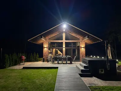 a house with a wooden deck at night at Galuonu vilos Ezero in Inturkė