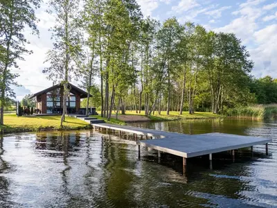 a dock in the middle of a lake with a cabin at Galuonu vilos Ezero in Inturkė