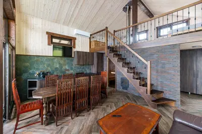 a living room with a staircase and a table and a dining room at Galuonu vilos Ezero in Inturkė
