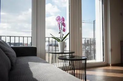 a living room with a couch and a vase with flowers on a window at Sunlit City Loft- Prime Views in Vilnius