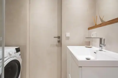 a bathroom with a washing machine and a sink at Silence of Uzupis - Self Check in in Vilnius