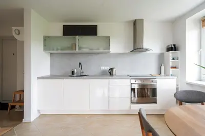 a kitchen with white cabinets and a sink and a table at Ducks in the yard - Self Check in in Vilnius