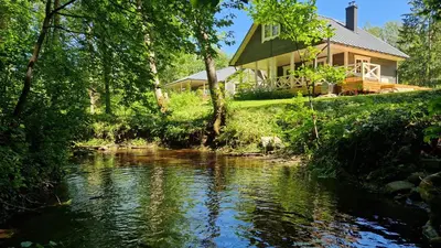 a house on a hill next to a river at Viensėdis in Anykščiai