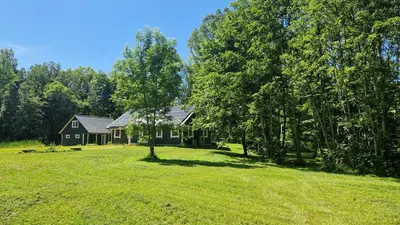 a house in the middle of a field with trees at Viensėdis in Anykščiai