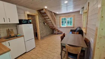 a kitchen with a table and a refrigerator and a staircase at Viensėdis in Anykščiai