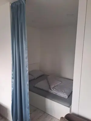 a small bed in a small room with a curtain at Prie Agluonos in Biržai
