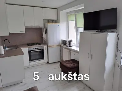 a kitchen with white cabinets and a refrigerator at Prie Agluonos in Biržai