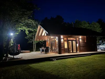 a small wooden house with a patio at night at Galuonu Vilos Rastas in Inturkė