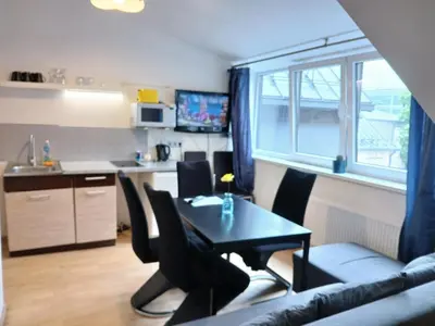 a living room with a table and chairs and a kitchen at Spacy apartment on Laisves avenue in Kaunas