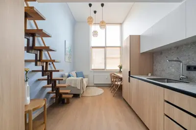 a kitchen with wooden cabinets and a spiral staircase at Lovely new loft in Vilnius centre self-check in in Vilnius