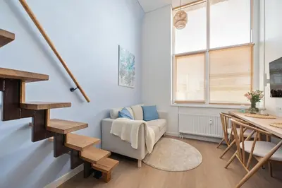 a living room with a staircase and a chair at Lovely new loft in Vilnius centre self-check in in Vilnius