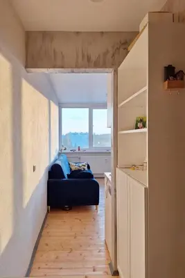 a living room with a blue couch and a window at Cozy studio apartment in Marijampolė