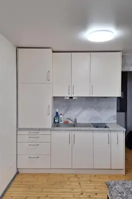 a white kitchen with white cabinets and a sink at Cozy studio apartment in Marijampolė