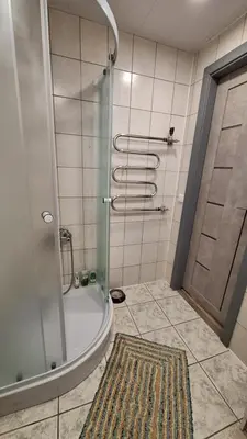 a bathroom with a shower and a tub with a rug at Cozy studio apartment in Marijampolė
