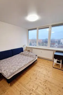 a bedroom with a bed in a room with windows at Cozy studio apartment in Marijampolė