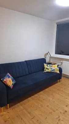 a blue couch in a living room with two pillows at Cozy studio apartment in Marijampolė