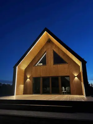 a timber clad house with a triangular roof at Modern design in quiet nature