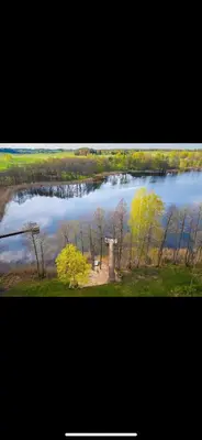 a view of a lake with trees and a tower at Čičirio krantas in Vėdariai