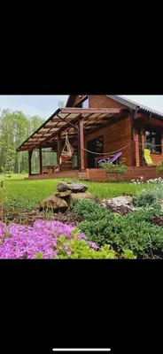 a log cabin with purple flowers in front of it at Čičirio krantas in Vėdariai