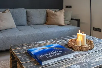 a coffee table with a book and candles on it at City Heart One-Bedroom, 15 in Vilnius