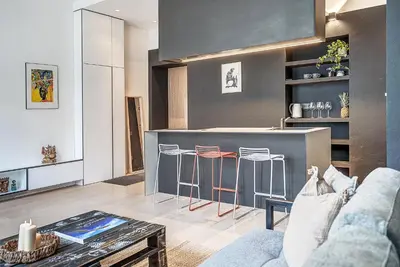 a living room with a kitchen with a counter and stools at City Heart One-Bedroom, 15 in Vilnius