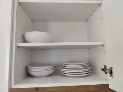 a white cabinet with plates and a sink in it at Stay Rokiškis apartments in Rokiškis