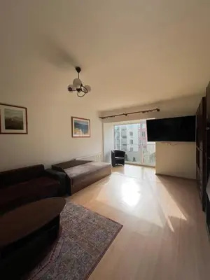 a living room with a couch and a flat screen tv at Cozy apartment near Santariskes in Vilnius