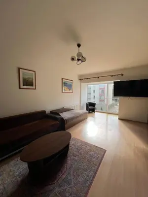 a living room with a couch and a table at Cozy apartment near Santariskes in Vilnius
