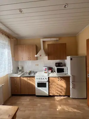 a kitchen with wooden cabinets and a white refrigerator at Cozy apartment near Santariskes in Vilnius