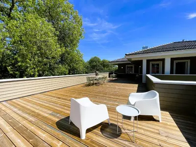a deck with white chairs and tables on a house at Kulpe Guest Rooms
