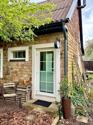 a brick house with a white door and a bench at Charming Cottage - Sauna - Central Location in Šiauliai