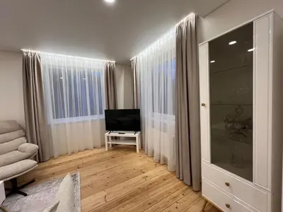 a living room with a television and a chair at Skaidiškės Guesthouse in Skaidiškės