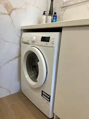 a white washing machine under a counter in a kitchen at Skaidiškės Guesthouse in Skaidiškės