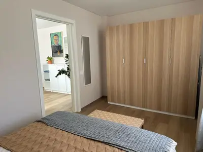 a bedroom with a bed and a large wooden cabinet at Maironis apartment - Cozy apartment in Raseiniai in Raseiniai