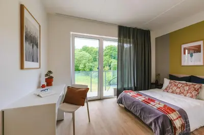 a bedroom with a bed and a desk and a window at Liv in Vilnius OZAS in Vilnius