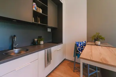 a kitchen with a sink and a wooden table at Liv in Vilnius OZAS in Vilnius