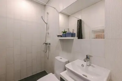 a white bathroom with a toilet and a sink at Liv in Vilnius OZAS in Vilnius