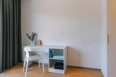 a white desk and a chair next to a wall at Liv in Vilnius OZAS in Vilnius