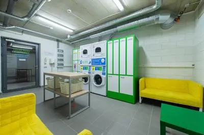 a laundry room with a washing machine and a yellow bench at Liv in Vilnius OZAS in Vilnius