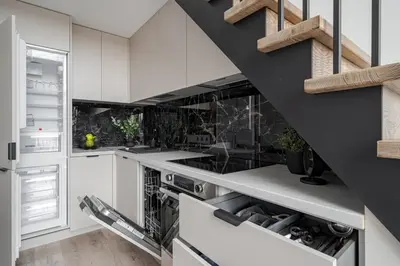 a kitchen with white cabinets and a black staircase at Brand New Loft 61 in Pakopi