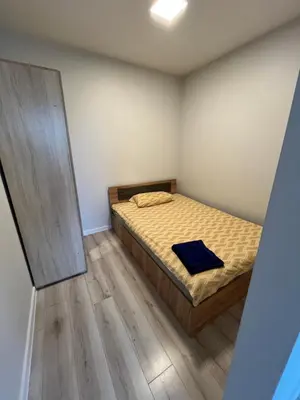 a small bedroom with a bed with a wooden floor at Apartamentai 2 in Raseiniai