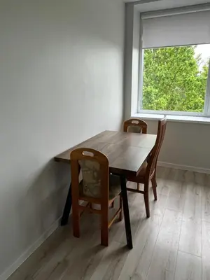 a wooden table and chairs in a room with a window at Apartamentai 2 in Raseiniai