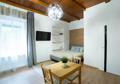 a living room with a table and a bed and a chandelier at Riverside Vilnius in Vilnius