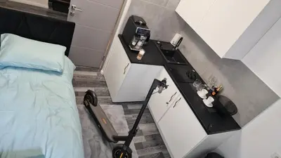 a room with a bed and a table with a vacuum at RentA Citywalk Flat in Kaunas