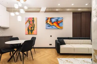 a living room with a table and two paintings on the wall at Aparthotel Nemunas in Druskininkai