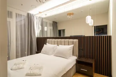 a bedroom with a large white bed with a mirror at Aparthotel Nemunas in Druskininkai