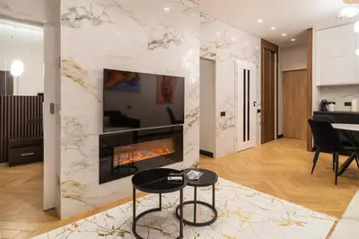 a living room with a fireplace and a table at Aparthotel Nemunas in Druskininkai