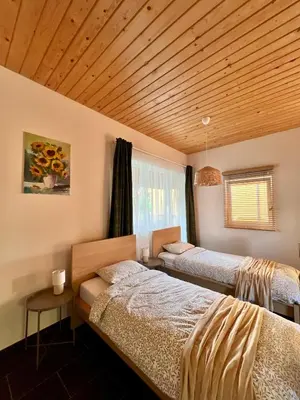 two beds in a room with a wooden ceiling at Apartamentai Jurbarko centre in Jurbarkas