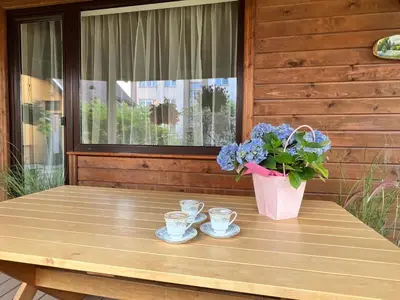 a table with two cups and a vase with flowers at Apartamentai Jurbarko centre in Jurbarkas